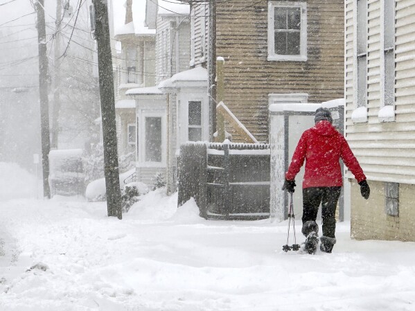 A person walks along a sidewalk as snow falls in Portsmouth, N.H., Sunday, Jan. 7, 2024. A major winter storm bringing up to a foot of snow and freezing rain to some communities spread across New England Sunday sending residents scurrying to pull out their shovels and snow blowers to clear sidewalks and driveways. Winter storm warnings and watches were in effect throughout the Northeast, and icy roads made for hazardous travel as far south as North Carolina. (AP Photo/Caleb Jones)
