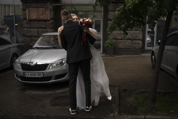 FILE - Newlyweds Nikita Timkov, 25, and his bride, Tamika Timkova, 23, dance to music playing in the street while waiting for their driver in Kyiv, Ukraine, Saturday, July 8, 2023. (AP Photo/Jae C. Hong, File)