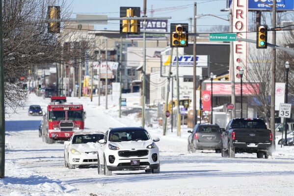 Traffic makes its way along 8th Ave. Tuesday, Jan. 16, 2024, in Nashville, Tenn. A snowstorm blanketed the area with up to eight inches of snow and frigid temperatures. (AP Photo/George Walker IV)