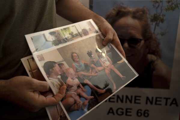 Nahal Neta, son of Adrienne Neta, 66, holds a photo of the nurse living in Kibbitz Be'eri missing since a Hamas surprise attack on the Gaza border, after a news conference by U.S. citizens whose relatives are missing, in Tel Aviv, Israel, Tuesday, Oct. 10, 2023. (AP Photo/Maya Alleruzzo)