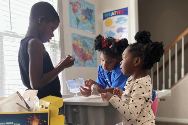 In this undated photo provided by Dalaine Bradley, Ahmad Waller, 11, Zion Waller, 10, and Drew Waller, 7, left to right, study during homeschooling, in Raleigh, N.C. (Courtesy of Dalaine Bradley via AP)