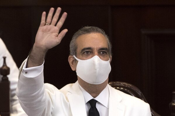 FILE - In this Aug. 16, 2020, file photo, Dominican Republic's President Luis Abinader, wearing a face mask amid the coronavirus pandemic, waves during his swearing-in ceremony in Santo Domingo, Dominican Republic. Abinader contracted and recovered from COVID-19 during his campaign. He spent weeks in isolation before the country’s July election. (Orlando Barria/Pool Photo via AP, File)