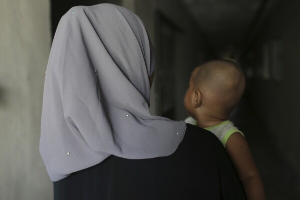 Rohingya child bride, T, age 16, holds her son in Kuala Lumpur, Malaysia, on Oct. 5, 2023. T left Bangladesh for Malaysia in 2022 for an arranged marriage with an older man. During her journey from Bangladesh, she was abused by a trafficker. She says her husband verbally abuses her and doesn't let her leave their apartment. (AP Photo/Victoria Milko)