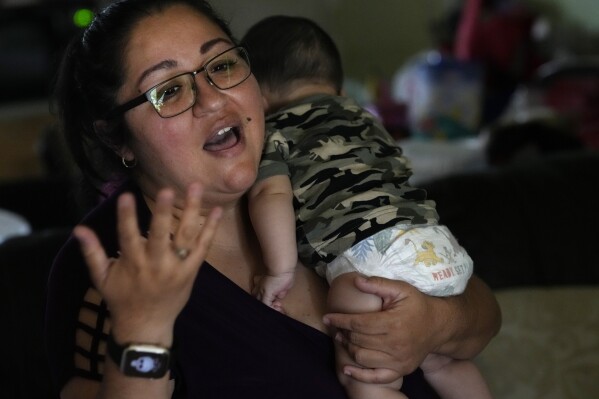 Hilda Garcia holds her infant son as she talks about the journey caring for Alexander, her 3-year-old son who is being treated for developmental delays at her West Chicago, Ill., home Tuesday, Aug. 8, 2023. From birth to age 3, children with developmental delays in all U.S. states and territories are entitled to Early Intervention services, which are crucial to helping tots develop the tools they need to thrive later on in life, experts say. But almost all states have reported program staffing shortages, and officials and health care providers say the situation has become critical post-pandemic, meaning kids like Alexander are left waiting months for the care they need, or age out of the program before they can access any services at all. (AP Photo/Charles Rex Arbogast)