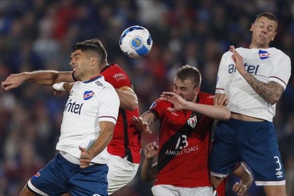 Luis Suarez, left, and Leonardo Coelho, right, of Uruguay's Nacional head the ball with Diego Churin, center left, and Klaus of Brazil's Atletico Goianiense during a Copa Sudamericana quarter-final first leg soccer match at the Gran Parque Central stadium in Montevideo, Uruguay, Tuesday, Aug. 2, 2022. (AP Photo/Matilde Campodonico)