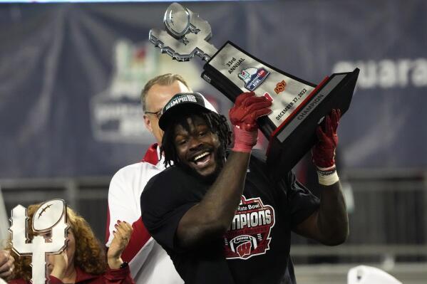 Wisconsin linebacker Jordan Turner kisses the trophy after defeating Oklahoma State 24-17 in the Guaranteed Rate Bowl NCAA college football game Tuesday, Dec. 27, 2022, in Phoenix. (AP Photo/Rick Scuteri)