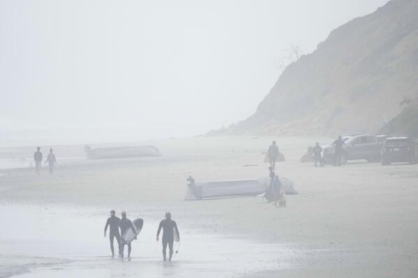Two boats, one overturned, sit on Blacks Beach, Sunday, March 12, 2023, in San Diego. Authorities say multiple people were killed when two suspected smuggling boats overturned off the coast San Diego, and crews were searching for other victims. (AP Photo/Gregory Bull)