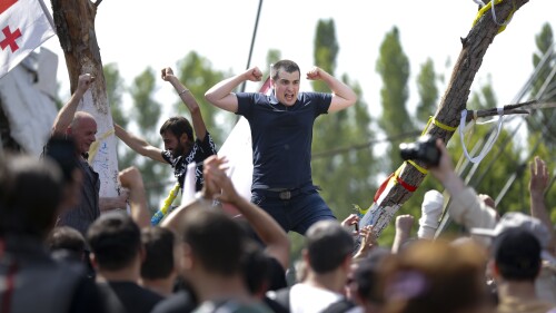 Georgian opponents of gay rights shout anti-LGBT festival slogans as they try to interfere with a pride party in Tbilisi, Georgia, Saturday, July 8, 2023.Hundreds of opponents of gay rights on Saturday swarmed the site of an LGBT festival in the capital of the country of Georgia, vandalizing the stage, setting fires and looting the event's bar. (AP Photo/Zurab Tsertsvadze)