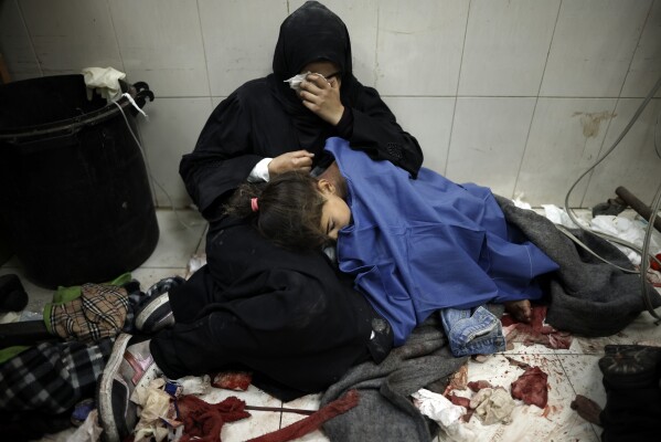A Palestinian woman cries as she sits next to her girl wounded in the Israeli bombardment of the Gaza Strip while receiving treatment at the Nasser Hospital in Khan Younis, Southern Gaza Strip, Monday, Jan. 22, 2024. (APPhoto/Mohammed Dahman)