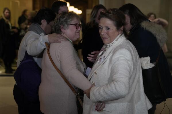 Injured victim, Nadege Renda, center left, reacts with survivors relatives at the end of the Nice attacks trial at the temporary Courtroom, in Paris, Tuesday, Dec. 13, 2022. A French court has given its verdict Tuesday in a trial over a truck attack more than six years ago by an Islamic State sympathizer that killed 86 people in the French Riviera city of Nice, handing all the eight people charged in connection with the atrocity prison terms ranging from two to 18 years. (AP Photo/Francois Mori)