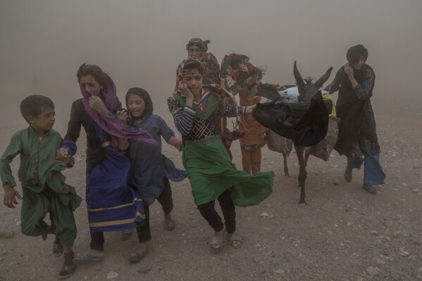 Afghan girls and women carry donated aid to their tents, while they are scared and crying from the fierce sandstorm, after an earthquake in Zenda Jan district in Herat province, western of Afghanistan, Thursday, Oct. 12, 2023. (AP Photo/Ebrahim Noroozi)