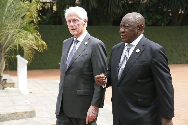 Former US President Bill Clinton, left, and South Africa's President Cyril Ramaphosa arrive to lay a wreath at a ceremony to mark the 30th anniversary of the Rwandan genocide, held at the Kigali Genocide Memorial, in Kigali, Rwanda, Sunday, April 7, 2024. Rwandans are commemorating 30 years since the genocide in which an estimated 800,000 people were killed by government-backed extremists, shattering this small east African country that continues to grapple with the horrific legacy of the massacres. (AP Photo/Brian Inganga)