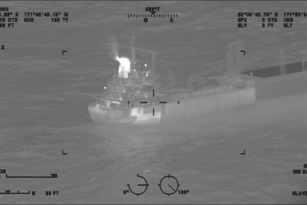 This image provided by the U.S. Coast Guard shows a reported fire aboard the 410-foot cargo vessel Genius Star XI, approximately 200 miles southwest of Dutch Harbor, Alaska on Thursday, Dec. 29, 2023. The large cargo ship with a fire in its hold is being kept 2 miles (3.22 kilometers) offshore of an Alaska port as a precaution while efforts are undertaken to extinguish the flames, the U.S. Coast Guard said Saturday. (Lt.Cmdr. Michael Salerno/U.S. Coast Guard via AP)