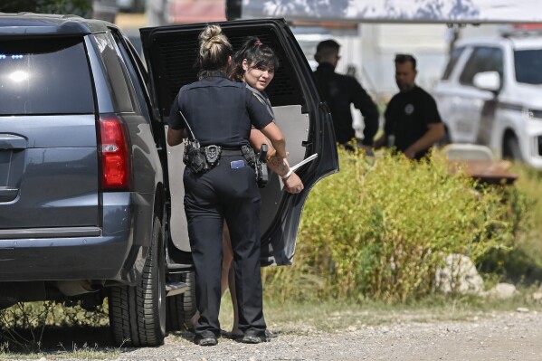 A Bexar County Sheriff Deputy, left, talks to a handcuffed woman during a law enforcement sting, Thursday, June 6, 2024, in San Antonio. (AP Photo/Darren Abate)
