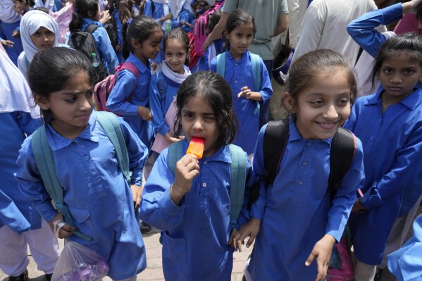 A student eats ice lolly as she leaves with others after school, as authorities announced reduced school hours due to soaring temperature, in Lahore, Pakistan, Tuesday, May 21, 2024. Authorities in Pakistan on Tuesday urged people to stay indoors as the country is hit by an extreme heat wave that threatens to bring dangerously high temperatures and yet another round of glacial-driven floods. (AP Photo/K.M. Chaudary)