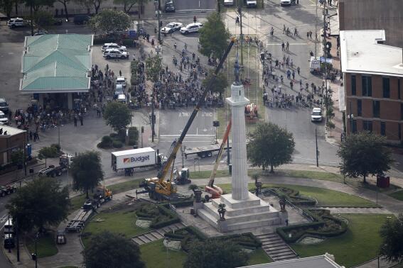 FILE -Workers prepare to take down the statue of former confederate general Robert E. Lee, which stands over 100 feet tall, in Lee Circle in New Orleans, Friday, May 19, 2017. A round patch of New Orleans green space where a larger-than-life statue of Confederate Gen.  Robert E. Lee once loomed over the landscape has officially been re-named Harmony Circle.  (AP Photo/Gerald Herbert, File)