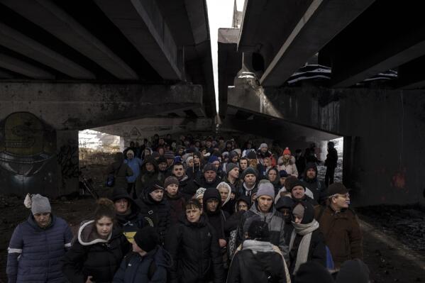 FILE - People crowd under a destroyed bridge as they try to flee, crossing the Irpin river on the outskirts of Kyiv, Ukraine, Tuesday, March 8, 2022. Russia's relentless digital assaults on Ukraine may have caused less damage than many anticipated. But most of its hacking is focused on a different goal that gets less attention but has chilling potential consequences: data collection. (AP Photo/Felipe Dana, File)