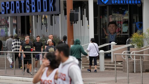 Fans walks past a sportsbook attached to the Footprint Center, Tuesday, March 14, 2023, in Phoenix. Major League Baseball — long the most gambling-averse of the U.S. leagues — now permits its players to be ambassadors for gambling companies. It’s the backdrop for an era of legal sports betting in the U.S. that’s brought in huge revenues but also has some experts sounding cautionary notes. (AP Photo/Matt York)