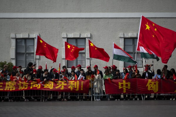 People wave Chinese and Hungarian flags as they wait for the arrival of Chinese President Xi Jinping outside the Buda Castle in Budapest, Hungary, Thursday, May 9, 2024. (AP Photo/Denes Erdos)