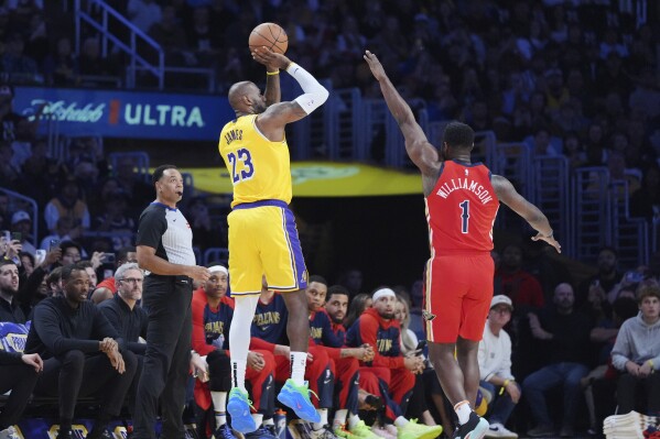 Los Angeles Lakers forward LeBron James, left, makes a 3-point basket over New Orleans Pelicans forward Zion Williamson (1) to go over the 50,000 career point mark during the first half of an NBA basketball game Tuesday, March 4, 2025, in Los Angeles. (AP Photo/Jae C. Hong)