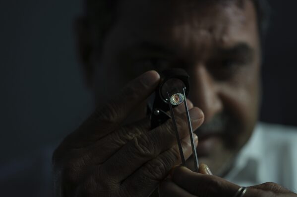 A worker inspects a polished diamond at Shree Ramkrishna Exports in Surat, India, on April 14, 2025. (AP Photo/Ajit Solanki)