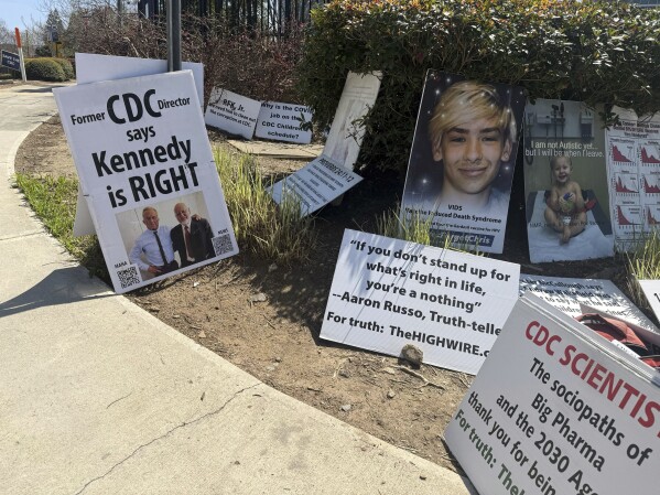 Signs placed by Mike Arnold, a supporter of Health Secretary Robert F. Kennedy Jr., are pictured as Arnold protests against the CDC outside the CDC campus in Atlanta, Thursday, March 27, 2025. (AP Photo/Kenya Hunter)