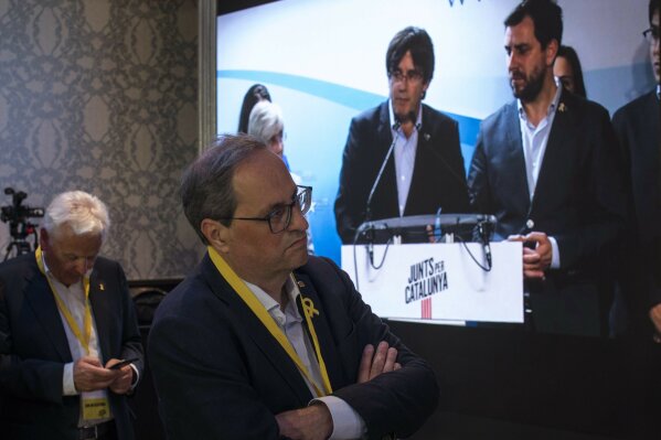 
              Regional Catalan President Quim Torra, centre, looks at former regional Catalan President Carles Puigdemont appearing on a screen during a video conference from Brussels, at the party headquarters in Barcelona, Catalonia, Spain, Sunday, May 26, 2019. Former Catalan regional president Carles Puigdemont, his ex-No. 2 Oriol Junqueras and former Catalan Cabinet member Toni Comín all won seats for separatist parties in Sunday's EU vote. That's according to provisional results released by Spain's Interior Ministry with 85% of the votes counted. (AP Photo/Emilio Morenatti)
            