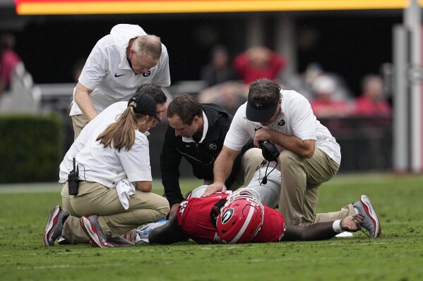Georgia head coach Kirby Smart, right, checks on injured offensive lineman Amarius Mims (65) during the first half of an NCAA college football game against South Carolina Saturday, Sept. 16, 2023, Ga. (AP Photo/John Bazemore)