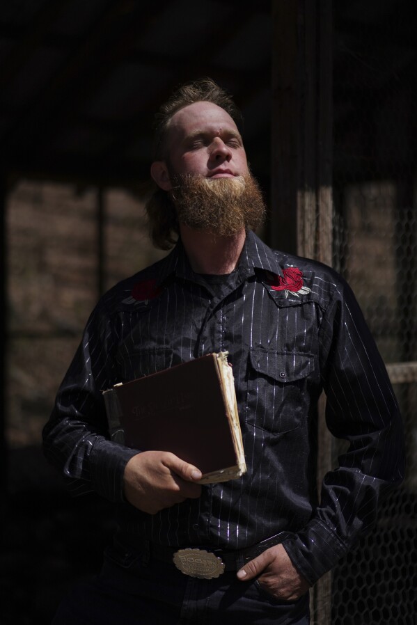 Isaac Green, 34, poses for a portrait with his copy of "The Sacred Harp" near a natural spring at Holly Springs Primitive Baptist Church in Bremen, Ga., on Sunday, March 32, 2025. (AP Photo/Jessie Wardarski)