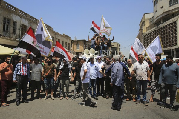 Demonstrators protest in front of the Iraqi central bank as currency plummets against the U.S. dollar, in Baghdad, Iraq, Wednesday, July. 26, 2023. Over the past two days, the market rate of the dollar jumped from 1,470 dinar per dollar to 1,570 dinar per dollar. (AP Photo/Hadi Mizban)