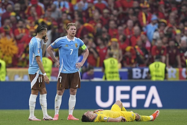  Belgium's Kevin De Bruyne, center, and Yannick Carrasco, left, gather next to Ukraine's Oleksandr Tymchyk at the end of a Group E match between Ukraine and Belgium at the Euro 2024 soccer tournament in Stuttgart, Germany, Wednesday, June 26, 2024. The match ended in a 0-0 draw. (AP Photo/Ariel Schalit)