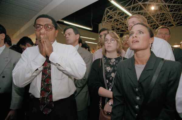 FILE - Christopher Odle, 36, a legal clerk from Crown Heights, Brooklyn, borough of New York, left, wipes away tears moments after hearing the news that O.J. Simpson was found not guilty of killing Nicole Brown Simpson and Ronald Goldman, in New York, Oct. 3, 1995. At right is Bernadette B. Incerto, 33. For many people old enough to remember O.J. Simpson's murder trial, his 1994 exoneration was a defining moment in their understanding of race, policing and justice. Nearly three decades later, it still reflects the different realities of white and Black Americans. (AP Photo/Clark Jones)