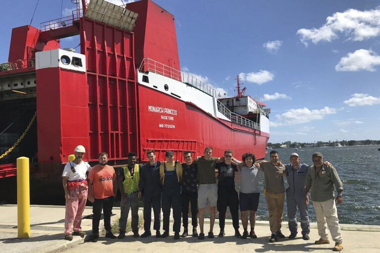 This photo provided by Ievgen Slautin of Ukraine, captain of the cargo ship Monarch Princess, shows him, second from left, with the six men who were with him on the ship abandoned by owners Teeters Agency & Stevedoring at the Port of Palm Beach in Riviera Beach, Fla., and other men in 2023. (Courtesy Ievgen Slautin via AP)