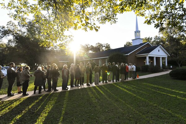 In this Sunday, Nov. 3, 2019, photo, the sun breaks the horizon as guests begin lining up to attend Sunday school class being taught by former President Jimmy Carter at Maranatha Baptist Church, in Plains, Ga. Guests begin arriving before dawn, some even the day before, spending the night in the parking lot, with hopes of attending the class. (AP Photo/John Amis)