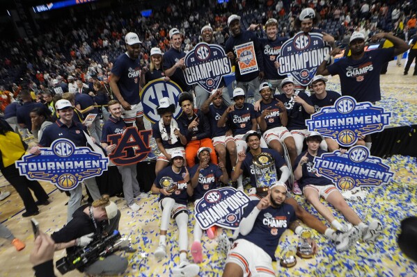 Auburn players pose for a team photo after defeating Florida in an NCAA college basketball game to win the Southeastern Conference tournament Sunday, March 17, 2024, in Nashville, Tenn. (AP Photo/John Bazemore)