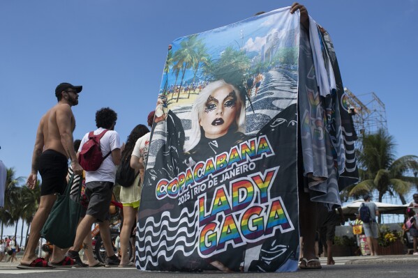 A seller hawks souvenir beach towels featuring Lady Gaga, in Rio de Janeiro, Thursday, May 1, 2025. Lady Gaga is in Rio to give a free concert, that will be held on Saturday, at Copacabana Beach. (AP Photo/Bruna Prado)