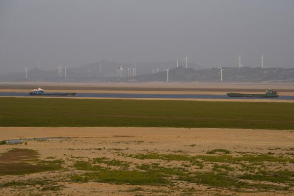 Ships pass through a narrow stretch of water over a dried up Poyang Lake in north-central China's Jiangxi province on Monday, Oct. 31, 2022. A prolonged drought since July has dramatically shrunk China’s biggest freshwater lake, Poyang. (AP Photo/Ng Han Guan)