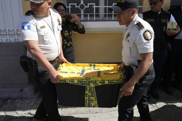 Police agents carry evidence collected from the Seed Movement political party headquarters, in Guatemala City, Friday, July 21, 2023. Guatemalan agents and police raided the offices of presidential candidate Bernardo Arevalo as part of an investigation into alleged wrongdoing in the party's formation. (AP Photo/Moises Castillo)
