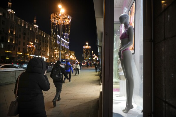 Pedestrians walk past a mannequin in a window of a fashion store in Tverskaya street in Moscow, Russia, Wednesday, March 6, 2024. The economy's resilience in the face of bruising Western sanctions is a major factor behind President Vladimir Putin's grip on power in Russia. (AP Photo/Alexander Zemlianichenko)