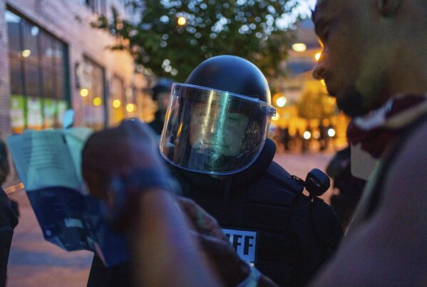 A protester shows a law enforcement officer a Bible verse in Grand Rapids, Mich., Wednesday, June 3, 2020. (Anntaninna Biondo/The Grand Rapids Press via AP)