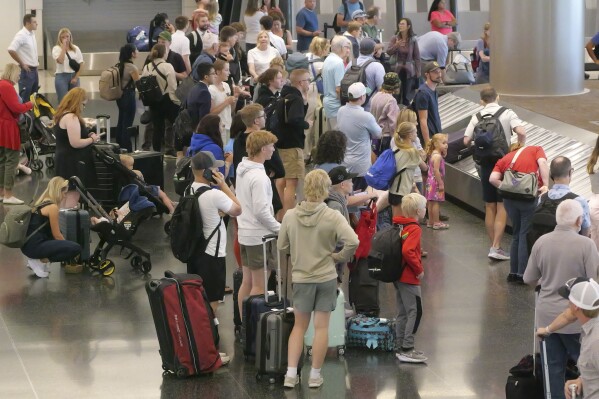 Holiday travelers wait for their luggage after arriving at Salt Lake City International Airport Wednesday, July 3, 2024, in Salt Lake City. (AP Photo/Rick Bowmer)