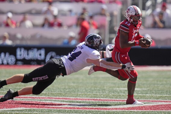 Utah quarterback Nate Johnson (13) breaks free from Weber State defensive end Brayden Wilson (94) tackle during the second half of an NCAA college football game Saturday, Sept. 16, 2023, in Salt Lake City. (AP Photo/Rick Bowmer)