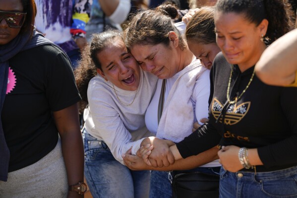 A sister of miner Santiago Mora, left, cries with other relatives as he is buried at the cemetery in La Paragua, Bolivar state, Venezuela, Thursday, Feb. 22, 2024. The collapse of an illegally operated open-pit gold mine in central Venezuela killed at least 14 people and injured several more, state authorities said Wednesday, as some other officials reported an undetermined number of people could be trapped. (AP Photo/Ariana Cubillos)