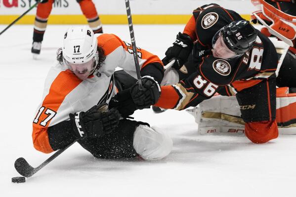 Anaheim Ducks defenseman Simon Benoit (86) takes control of the puck while falling with Philadelphia Flyers center Zack MacEwen (17) during the third period of an NHL hockey game in Anaheim, Calif., Tuesday, Jan. 4, 2022. (AP Photo/Ashley Landis)