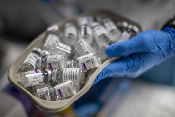 FILE - A nurse holds vials of AstraZeneca vaccine against COVID-19 during a vaccination campaign at WiZink indoor arena in Madrid, April 9, 2021. Police in Italy, Austria, Romania and Slovakia arrested 22 people Thursday as part of an investigation into the suspected siphoning of hundreds millions of euros in post-pandemic relief funds from the European Union. (AP Photo/Manu Fernandez, File)