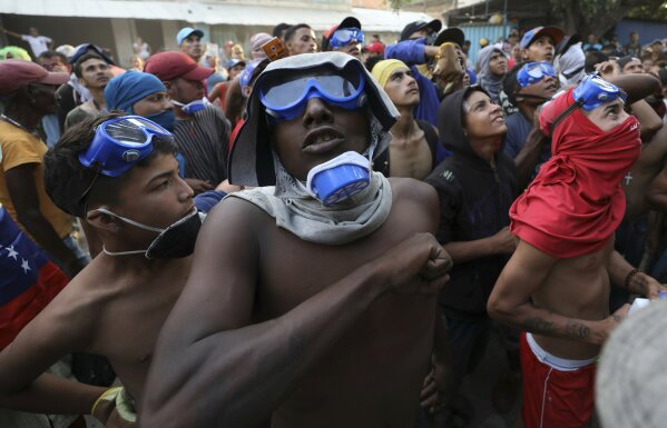 
              Venezuelan migrants under the Simon Bolivar International Bridge plead for people to support them with food and water so they can continue protesting in La Parada near Cucuta, Colombia, Sunday, Feb. 24, 2019, on the border with Venezuela. A U.S.-backed drive to deliver foreign aid to Venezuela on Saturday met strong resistance as troops loyal to President Nicolas Maduro blocked the convoys at the border and fired tear gas on protesters. (AP Photo/Fernando Vergara)
            