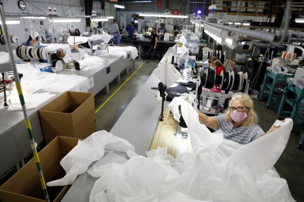 Angie Moorefield unfolds material to begin sewing a disposable gown at Burlington Medical in Newport News Wednesday, May 6, 2020. The manufacturing business recently shifted from producing radiation protection gear for medical facilities to in-demand personal protective equipment such as masks, gowns and plastic face shields. (Jonathon Gruenke/The Virginian-Pilot via AP)