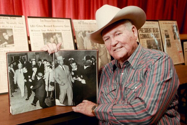 FILE - In this Dec. 11, 1998 file photo, shows Jim Leavelle in Stafford, Kansas holding the iconic 1963 photograph, as he escorted Lee Harvey Oswald moments before he is shot in Dallas.  Leavelle, the longtime Dallas lawman has died, Thursday, Aug. 29, 2019. He was 99.  (Sandra J. Milburn/The Hutchinson News via AP)