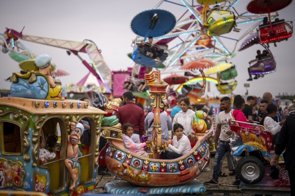 Children sit in a carousel at a fair in Hagioaica, Romania, Saturday, Sept. 16, 2023. (AP Photo/Andreea Alexandru)