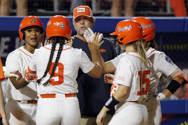 Oklahoma State coach Kenny Gajewski, middle, talks to players, from left, Morgyn Wynne, Chyenne Factor (9), Rachel Becker (15) and Kiley Naomi during a Utah pitching change in the second inning of an NCAA softball Women's College World Series game Friday, June 2, 2023, in Oklahoma City. (AP Photo/Nate Billings)